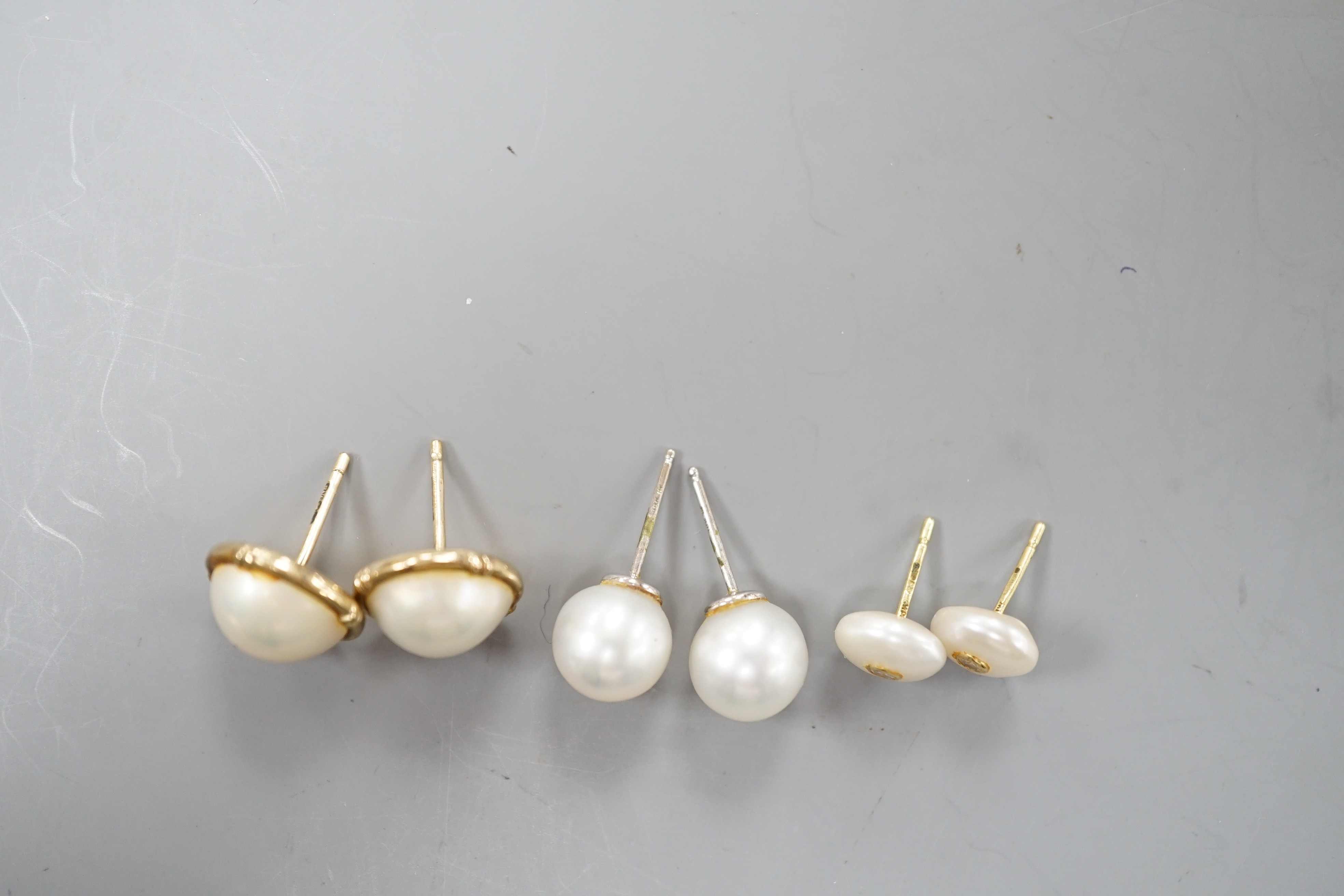 A pair of 18ct and cultured pear ear studs, a pair 9ct gold and mabe pearl ear studs and a pair of 18k, cultured pearl and diamond set ear studs (all lacking butterflies).
